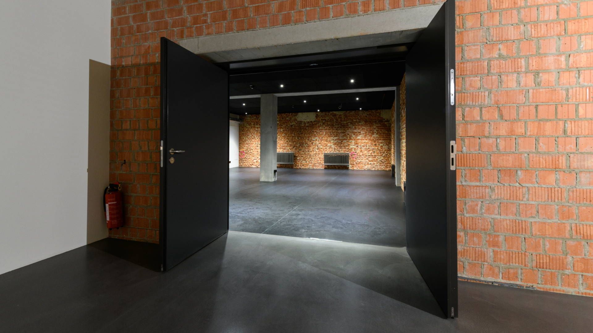 Die breiten Türen, die indirekte Beleuchtung machen das Studio mit seinen Backsteinwänden zu einem kleinen und intimen Raum.