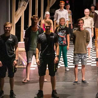 Junge Menschen posieren auf einer Bühne und halten Abstand zueinander